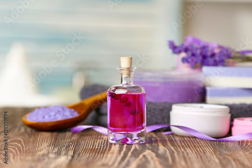 Bottle of lavender essential oil and body care products on background