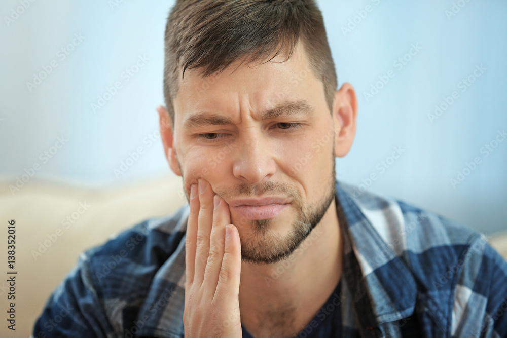 Handsome young man suffering from toothache at home, closeup