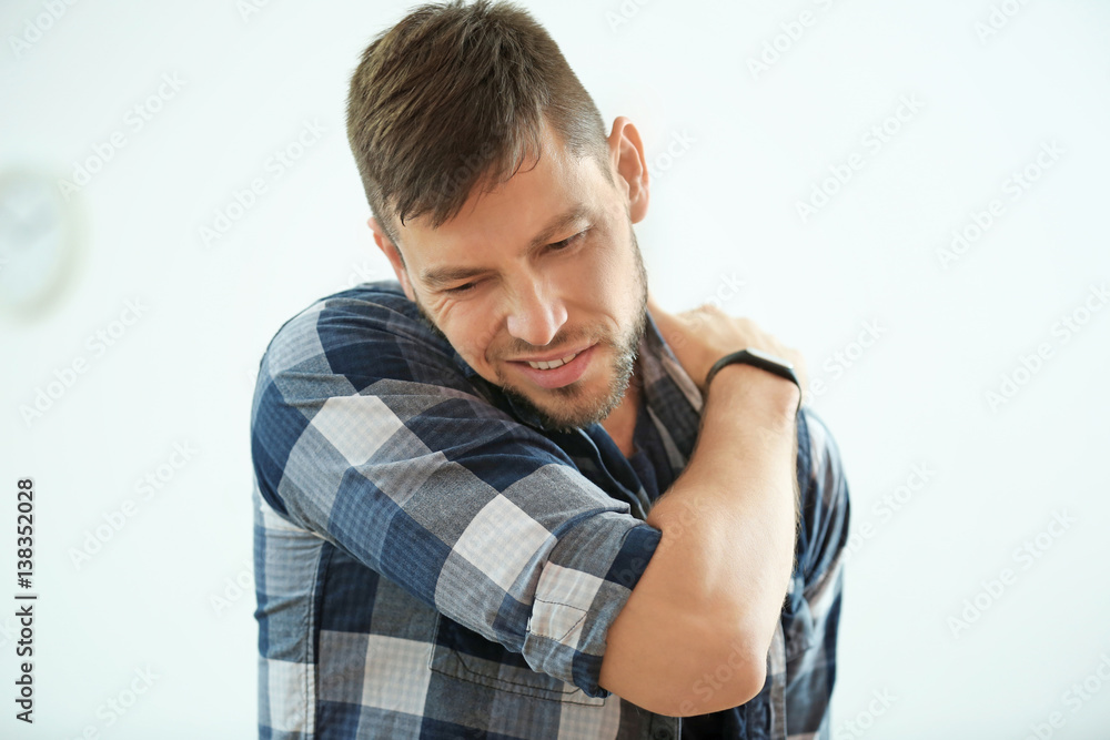 Handsome young man suffering from pain in shoulder at home Handsome young man suffering from pain in shoulder at home