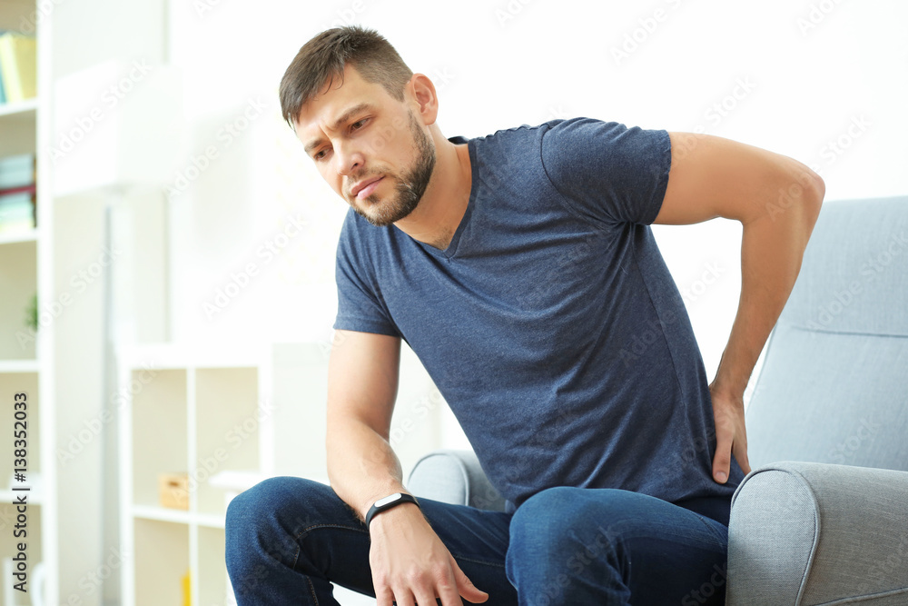 Handsome young man suffering from backache at home Handsome young man suffering from backache at home