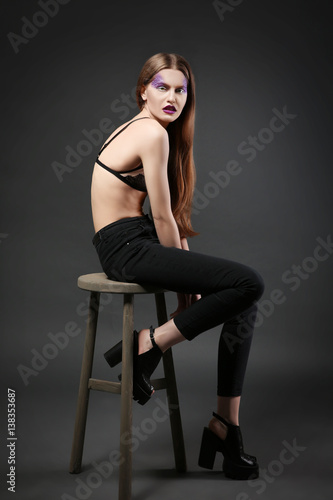 Young model with creative makeup on dark background