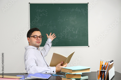 Handsome young teacher sitt...
