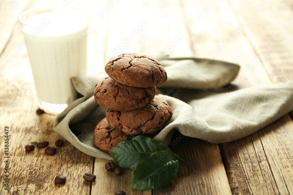 Delicious coffee cookies on napkin and glass of milk on wooden table Delicious coffee cookies on napkin and glass of milk on wooden table