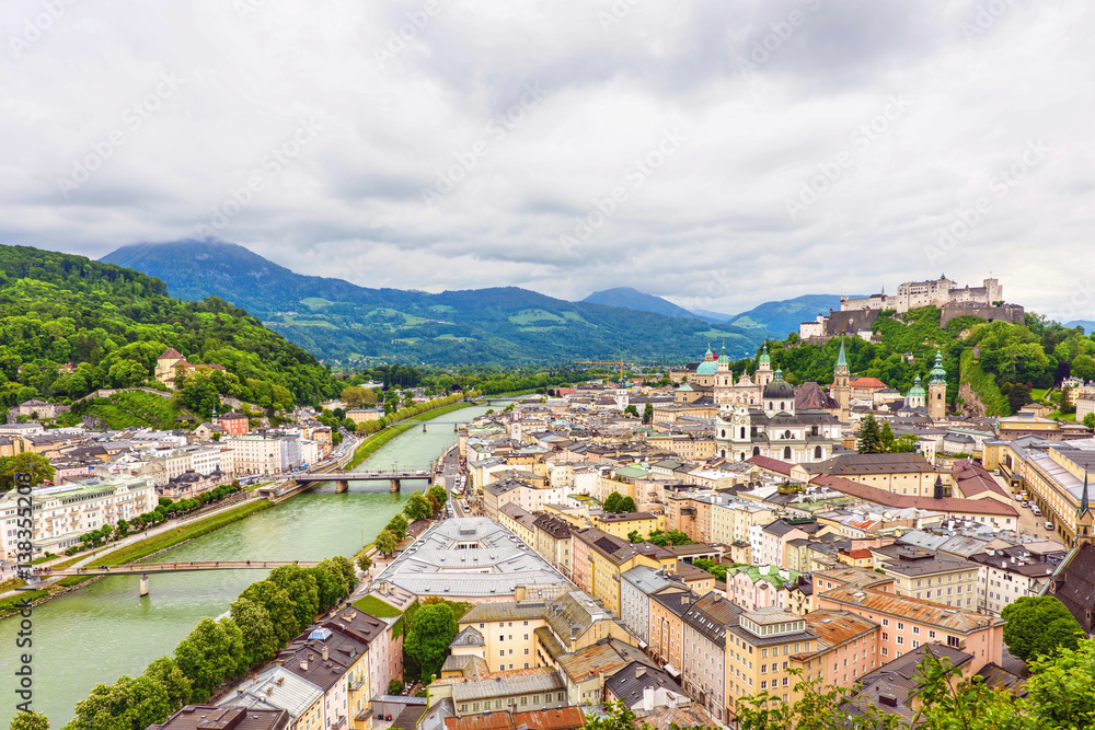 Panoramic view over stadt salzburg with salzach river, rainy day, bridge, castle and mountains, austria