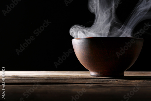 Bowl with hot water on dark background