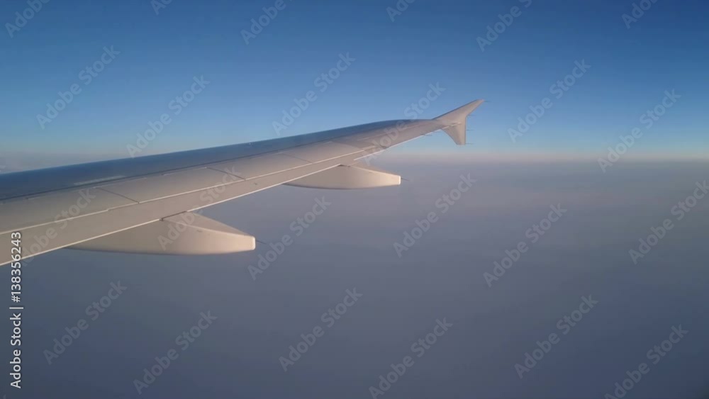 4k.Wing of airplane flying above clouds in the sky. View through an airplane window. 4k.Wing of airplane flying above clouds in the sky. View through an airplane window.