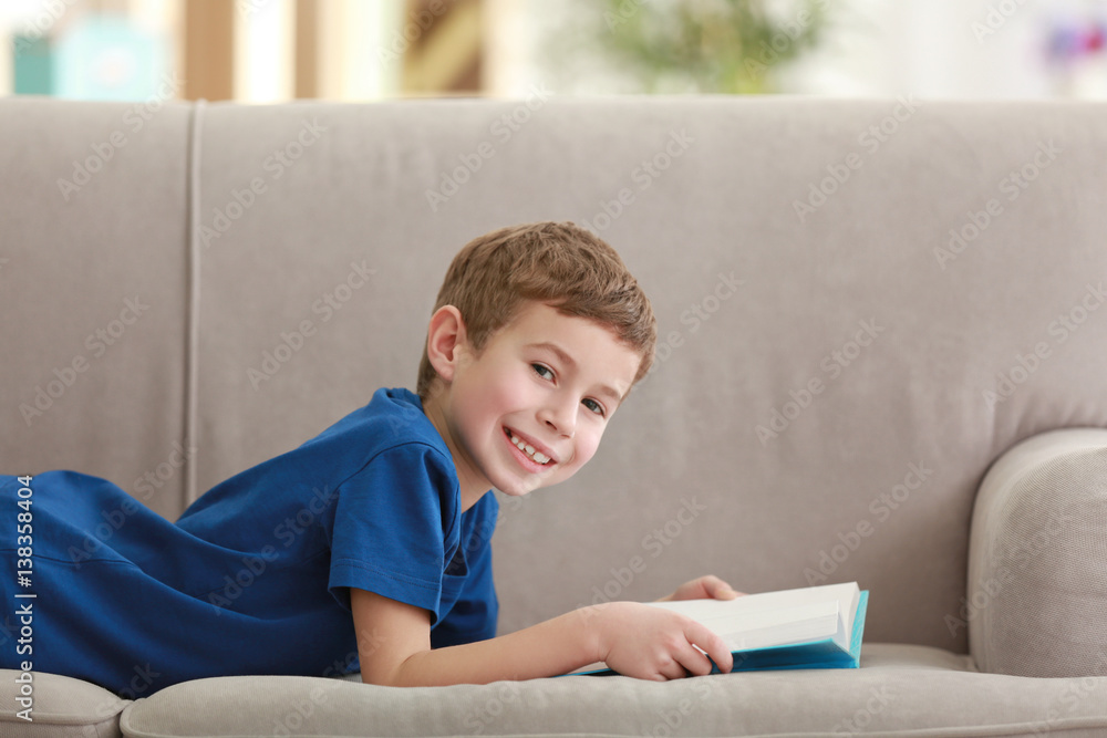 Little boy reading book on sofa indoors Little boy reading book on sofa indoors