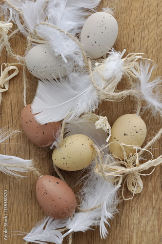 œufs de Pâques décoratifs et plumes sur fond bois