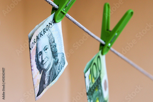 Green banknotes 100 euro and 100 swedish crownes in a green clothes peg photo