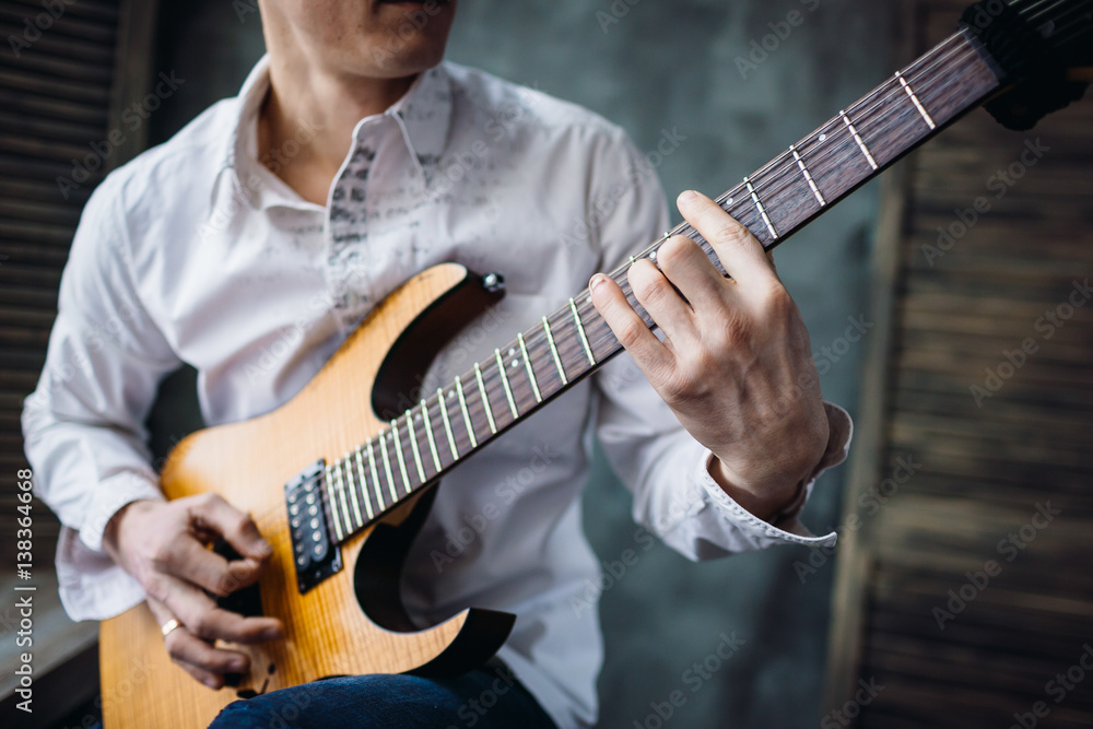 Man's hand touches string of classic electric guitar