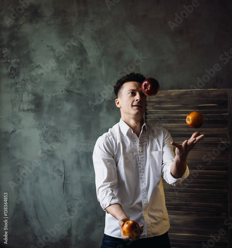 Awesome man in white shirt juggles with red apples