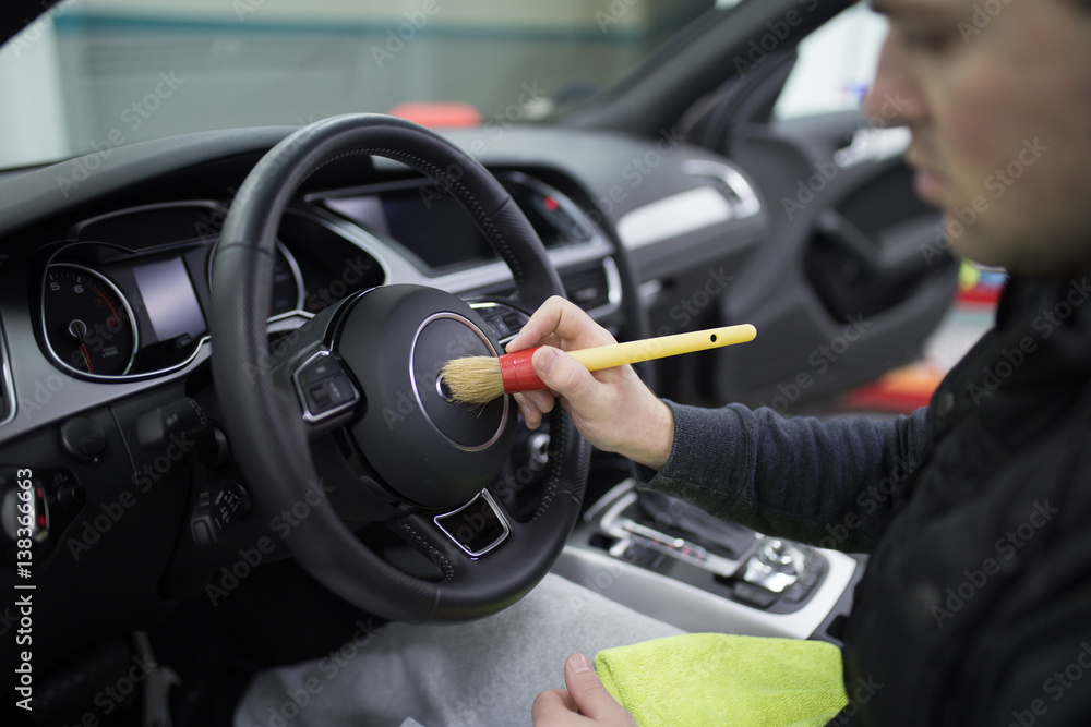 A man cleaning car interior, car detailing (or valeting) concept. Selective focus. A man cleaning car interior, car detailing (or valeting) concept. Selective focus.