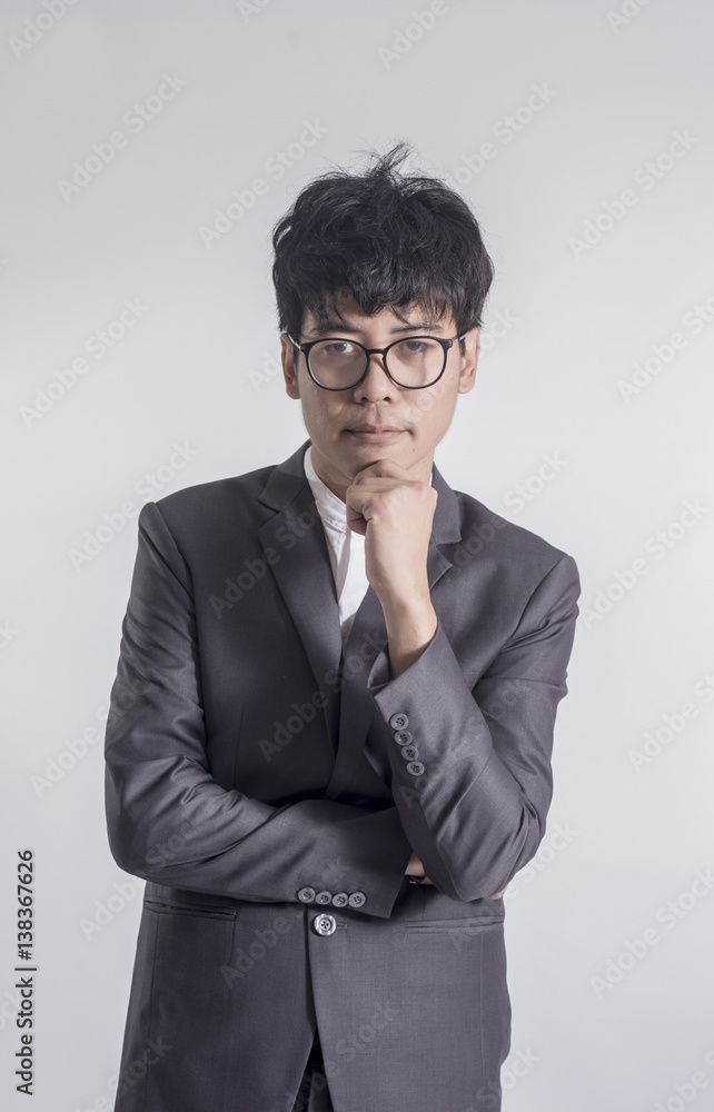 Young handsome man in gray suit and glasses looking at copy-space thinking or dreaming with gray background Young handsome man in gray suit and glasses looking at copy-space thinking or dreaming with gray background