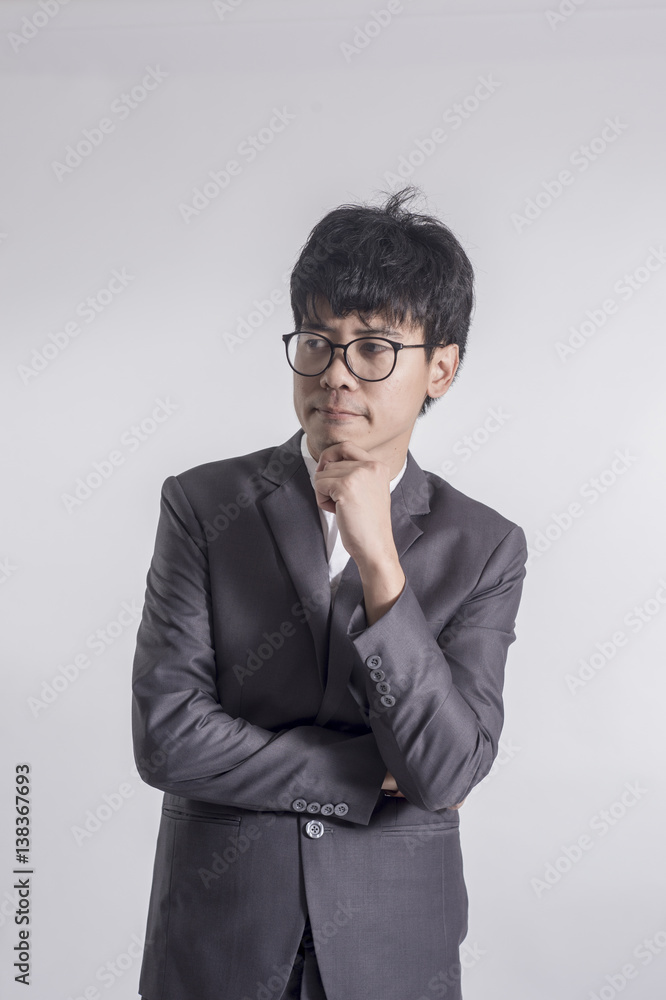 Young handsome man in gray suit and glasses looking at copy-space thinking or dreaming with gray background Young handsome man in gray suit and glasses looking at copy-space thinking or dreaming with gray background