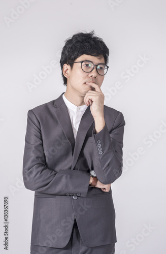 Young handsome man in gray suit and glasses looking at copy-space thinking or dreaming with gray background