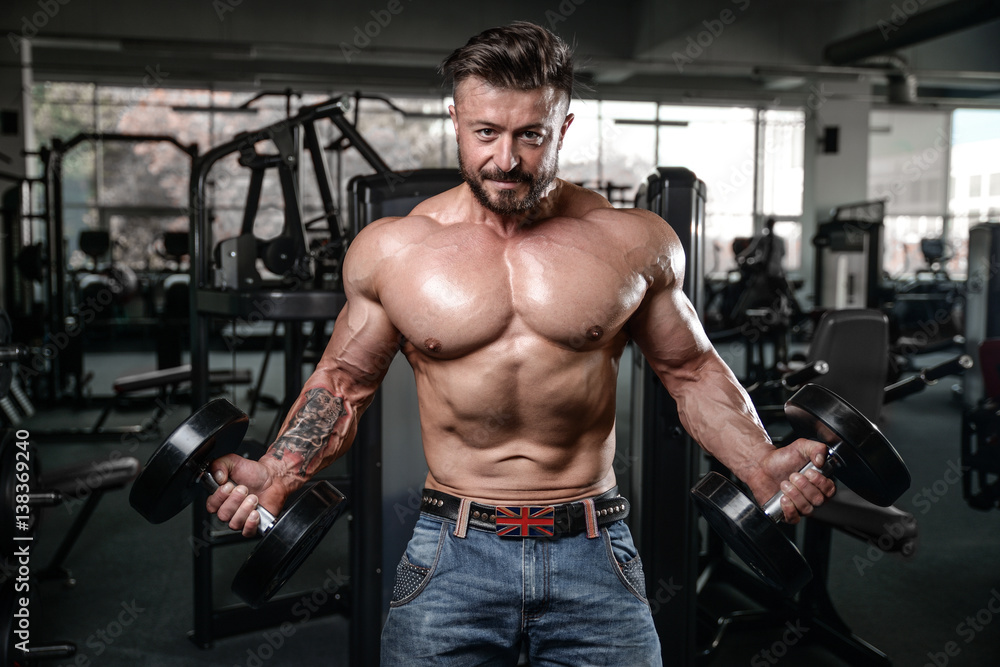 Brutal strong bodybuilder man pumping up muscles and train gym Brutal strong bodybuilder man pumping up muscles and train gym