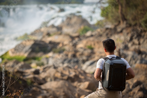 The man backpack drone travel in khonephapheng fall champasak Laos. Man carrying bag drones Travel in Laos. photo