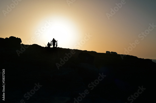 silhouette of fishermen on a cliff at dusk