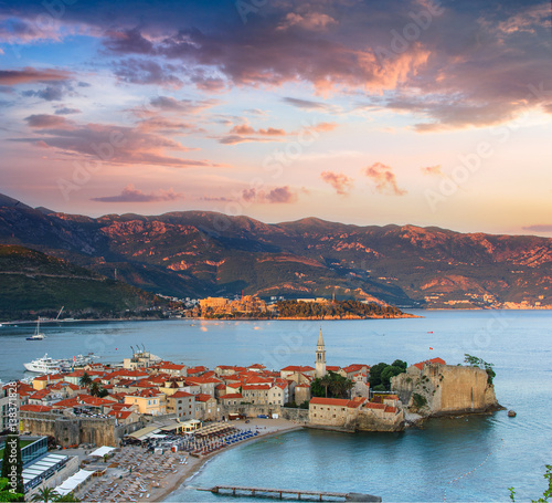 View of old town Budva, sea bay and mountains at distance. Colorful sky at sunset. Montenegro. Adriatic sea.