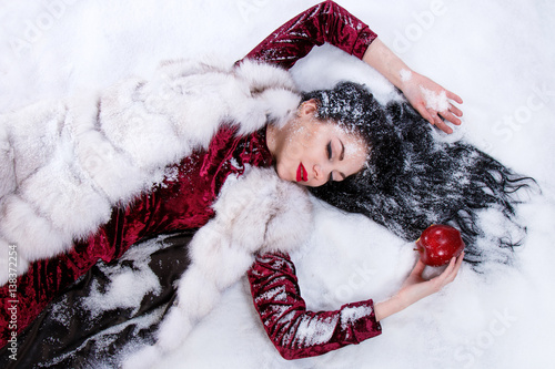 Woman laying on a snow near the bitten apple photo