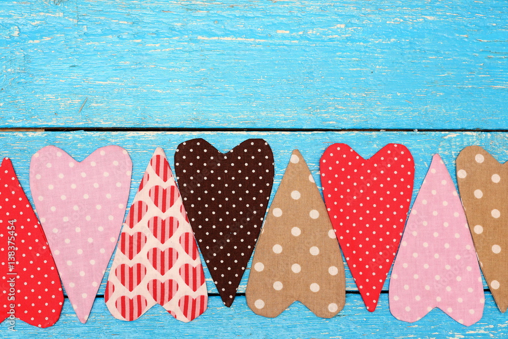 Obraz premium Colorful handmade hearts from fabric on background of blue boards. Love and romance. Feelings