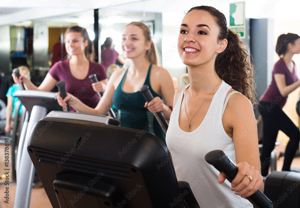 females training on elliptical trainers in fitness club