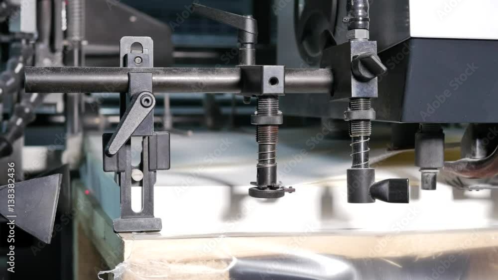 Passing white paper by a machine in an envelopes factory, close up Passing white paper by a machine in an envelopes factory, close up