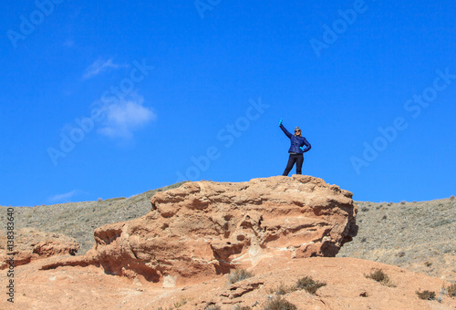 Happy woman standing on the top of the hill with raised hands and enjoy the view
