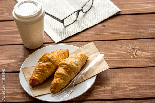 Business cup of coffee with croisant and newspaper on desk