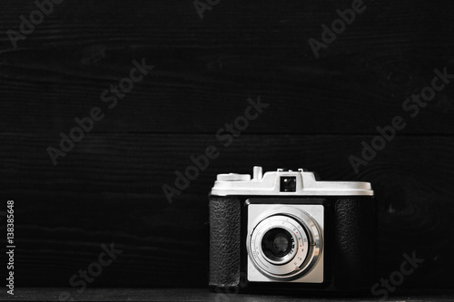 Retro photo camera on a black wooden background