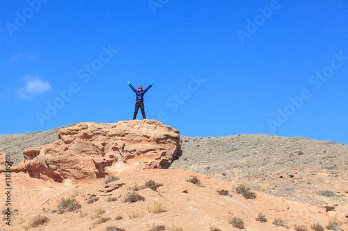 Happy woman standing on the top of the hill with raised hands and enjoy the view