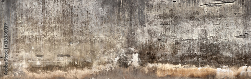 Brudna ściana z połamanym tynkiem cementowym.
