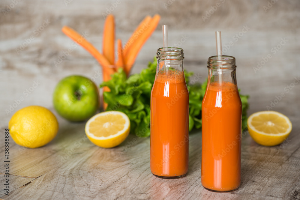 Fresh carrot juice in bottles on a grey wooden table Fresh carrot juice in bottles on a grey wooden table