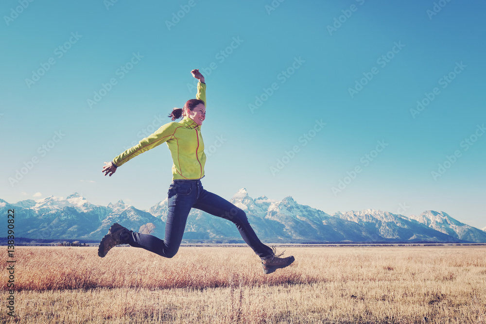 Retro stylized picture of a happy young woman jumping on a mountain meadow, Grand Teton National Park, Wyoming, USA. Retro stylized picture of a happy young woman jumping on a mountain meadow, Grand Teton National Park, Wyoming, USA.