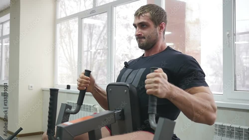 Athlete muscular bodybuilder training on simulator in the gym Athlete muscular bodybuilder training on simulator in the gym