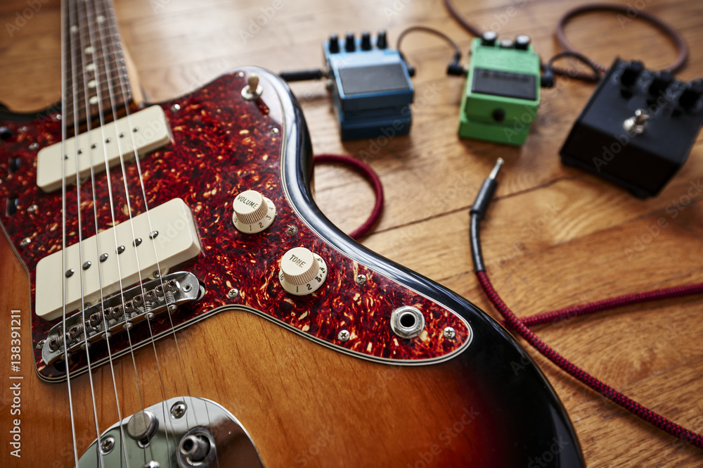 Naklejka premium an electric guitar with cables and pedals
