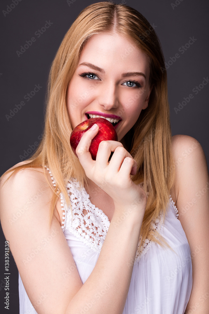 Portrait d'une jeune femme souriante croquant dans une pomme Portrait d'une jeune femme souriante croquant dans une pomme