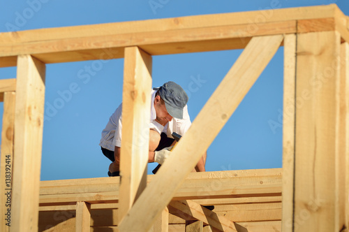 The young man, a builder builds a wooden frame house