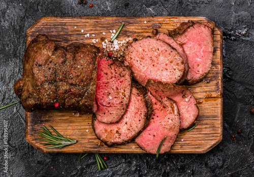Roast beef on cutting board with salt and pepper. Top view.