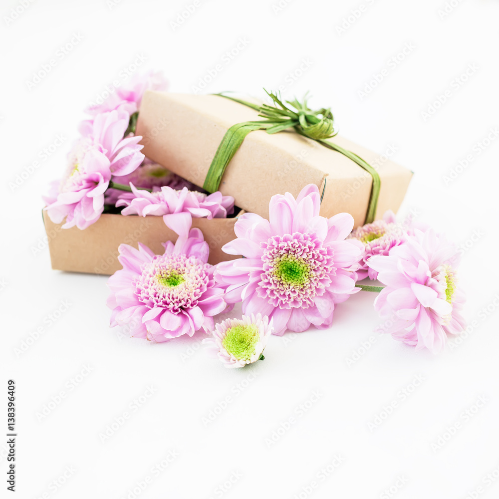 Craft gift box and pink flower on white background. Flat lay, top view. Floral background.