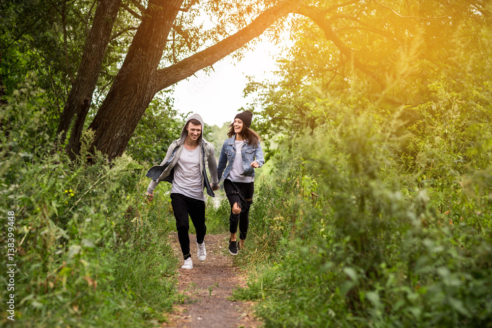 Toned photo of couple in love, man and woman in denim clothing running outdoor. Sport training Toned photo of couple in love, man and woman in denim clothing running outdoor. Sport training