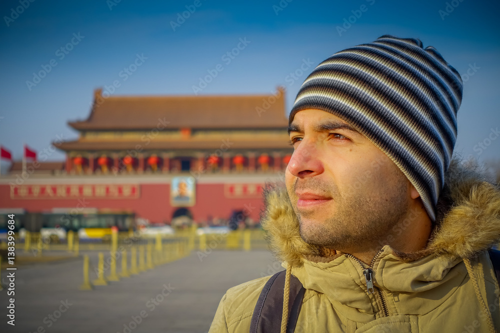 BEIJING, CHINA - 29 JANUARY, 2017: Hispanic tourist on Tianmen square looking around, famous forbidden city building in background, beautiful blue sky