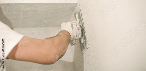 Construction worker plastering a wall with a spatula