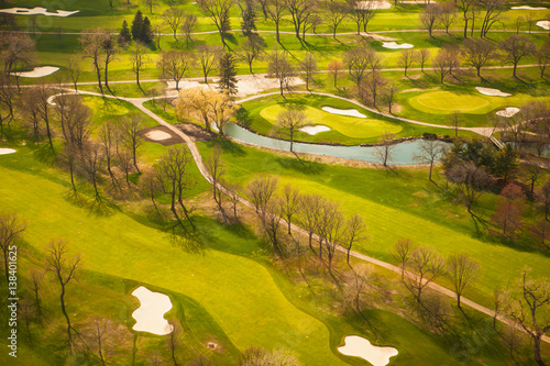 bare, spring trees throw shadows on a golf course near Chicago, Illinois