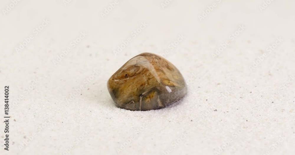 Petrified wood rotating on white sand surface. Semi precious gemstone which contains tiger’s eye. Clip is loopable.
