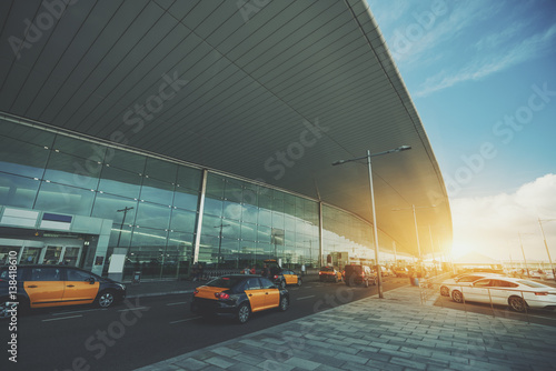 Cabstand in front of modern airport doors in Barcelona, cabrank with a lot of taxis near windowed facade of contemporary Airport terminal in Spain with road, long ceiling and parking lot