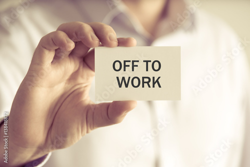 Businessman holding OFF TO WORK message card