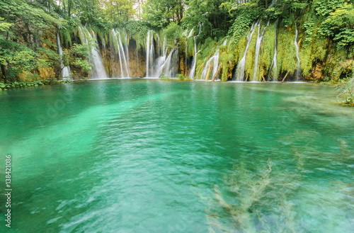 Fototapeta Naklejka Na Ścianę i Meble -  Multiple stunning waterfalls cascade into a vibrant turquoise lake at one of the oldest   and most visited national parks in Europe, Plitvice Lakes National Park.