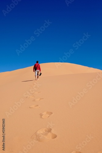 Man walking on sand dunes to the sky. Coral Pink Sand Dunes State Park. Cedar City. Kanab. Utah. United States.