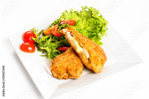 Fried golden chicken with cheese and vegetables on plate isolated at white background.